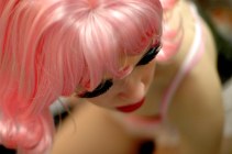 With her makeup, including feathered fake eyelashes, done and her costume almost finished, Baker adjusts her blond wig in the mirror to transform into Barbie. She completed the outfit with a pink short-sleeved collared shirt, which she attached Velcro to so that McGinnis could remove it easily during the performance. (Eugene OR, 2007)